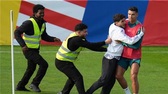 Ein Fan sprintet in Gütersloh auf den Trainingsplatz und umarmt Portugals Superstar Cristiano Ronaldo.