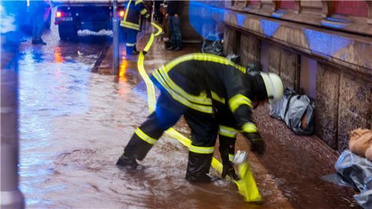 Ein Feuerwehr-Mitarbeiter verlegt einen Schlauch, um Hochwasser in Flensburg abzupumpen. (Archivbild)