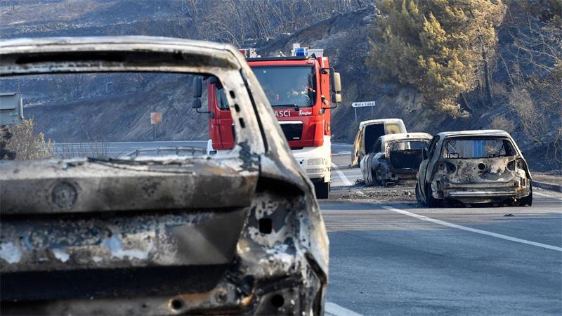 Waldbrand an der Adria: ein Toter, Verletzte, Zerstörungen Ein Feuerwehrfahrzeug fährt nach einem Waldbrand an der kroatischen Adria zwischen ausgebrannten Autos hindurch.