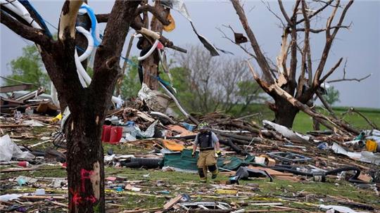 Ein Feuerwehrmann geht in Greenfield, Iowa, zwischen von einem Tornado zerstörten Häusern umher.