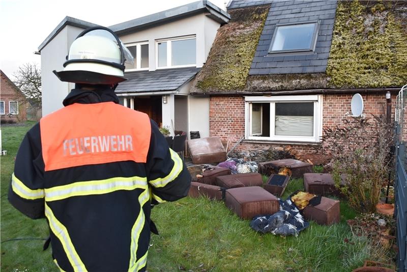 Ein Feuerwehrmann hat die Reste eines verbrannten Sofas im Blick. Foto: Vasel
