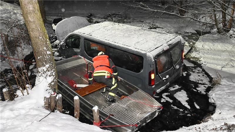 Ein Feuerwehrmann in einem Rettungsboot inspiziert einen Transporter in einem Löschteich.