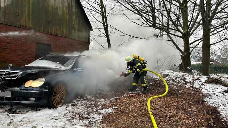 Auto steht in Pippensen in Flammen Ein Feuerwehrmann löscht den Brand.
