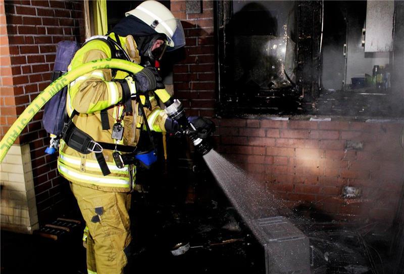 Ein Feuerwehrmann löscht den Brand in dem Mehrfamilienhaus in der Zeppelinstraße. Foto: Feuerwehr