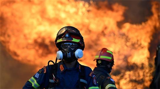 Ein Feuerwehrmann steht vor den lodernden Flammen nordwestlich von Athen.