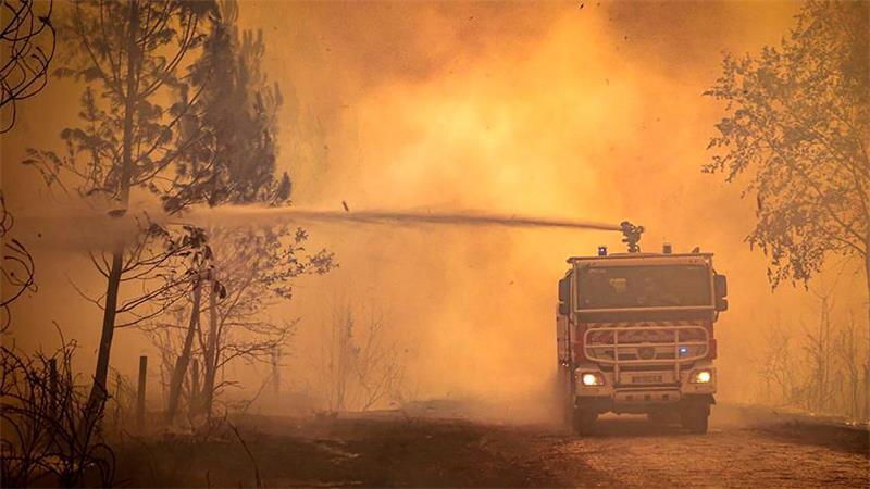 Ein Feuerwehrwagen sprüht Flüssigkeit auf einen Waldbrand in der Region Bordeaux. (Archivbild)