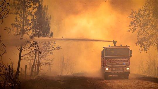 Ein Feuerwehrwagen sprüht Flüssigkeit auf einen Waldbrand in der Region Bordeaux. (Archivbild)