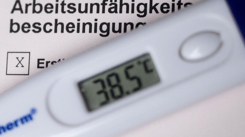 Krankschreibung in der Kündigungsfrist provoziert Zweifel Ein Fieberthermometer liegt auf einer Arbeitsunfähigkeitsbescheinigung.