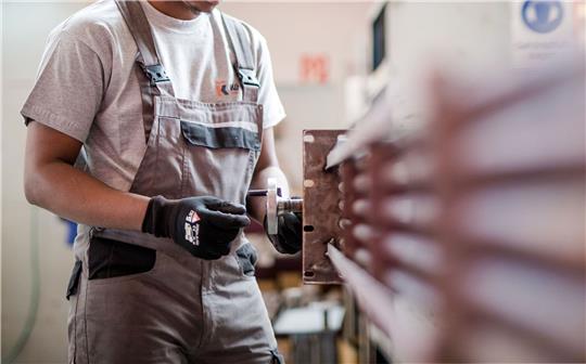 Ein Flüchtling aus Somalia arbeitet während eines Praktikums bei einem Industrieunternehmen in der Produktion. Es gibt Forderungen, die Arbeitsaufnahme für Flüchtlinge zu erleichtern.