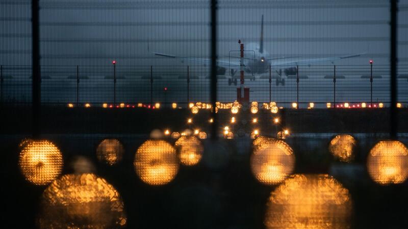 Flughafen Hamburg tritt Wasserstoff-Netzwerk von Airbus bei Ein Flugzeug landet hinter Signallichtern auf einem Flughafen.