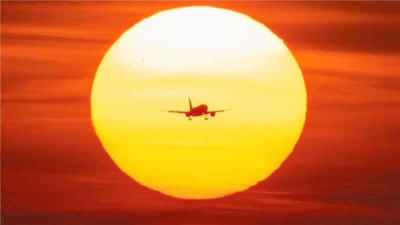 Ein Flugzeug setzt vor der untergehenden Sonne auf dem Flughafen Frankfurt zum Landeanflug an. 