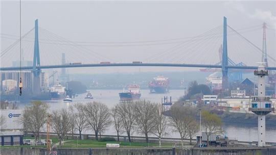 Ein Frachtschiff (vorne) und das Hapag-Lloyd Containerschiff „Potomac Express“ fahren unter der Köhlbrandbrücke her.