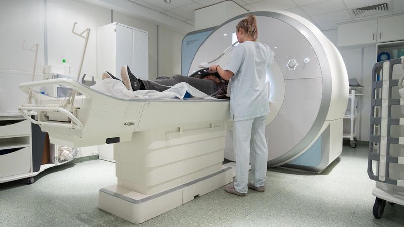 Ein Frau liegt in der Radiologie in einem Gerät zur Magnetresonanztomographie (MRT) (gestellte Szene).