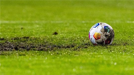 Ein Fußball liegt am Elfmeterpunkt im matschigen Rasen.