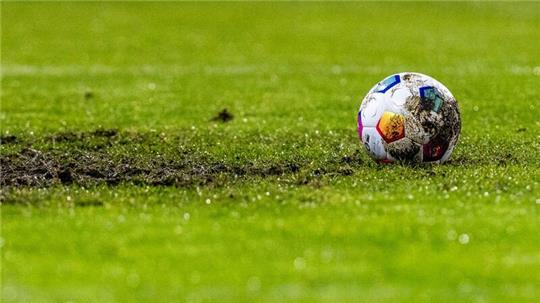 Ein Fußball liegt am Elfmeterpunkt im matschigen Rasen.