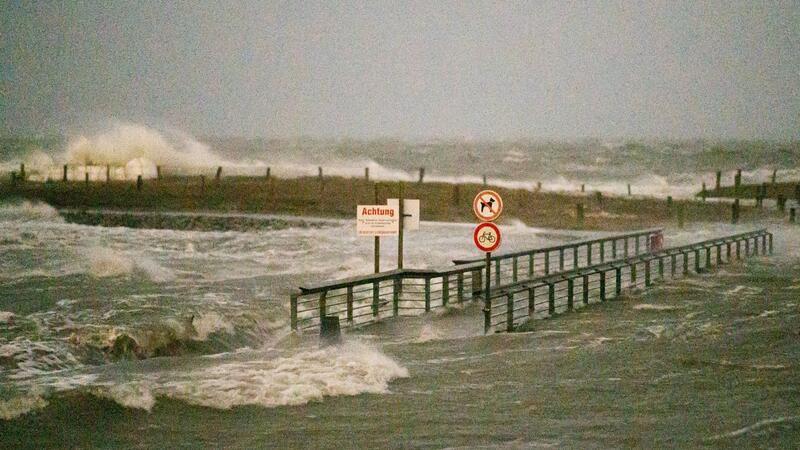 Ein Fußgängerübergang wird während eines Sturms von den Wellen der Nordsee umspült.