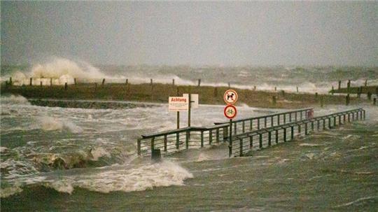 Ein Fußgängerübergang wird während eines Sturms von den Wellen der Nordsee umspült.