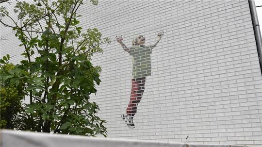 Ein Gedenkgarten soll an die getöteten Kinder erinnern. An einer Hauswand: Ein Kind, das einen Drachen steigen lässt.