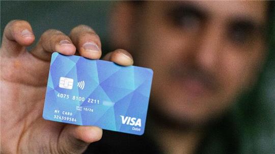 Ein Geflüchteter hält eine Debitcard in der Hand (Symbolbild).