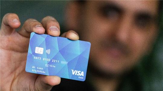 Ein Geflüchteter hält eine Debitcard in der Hand.