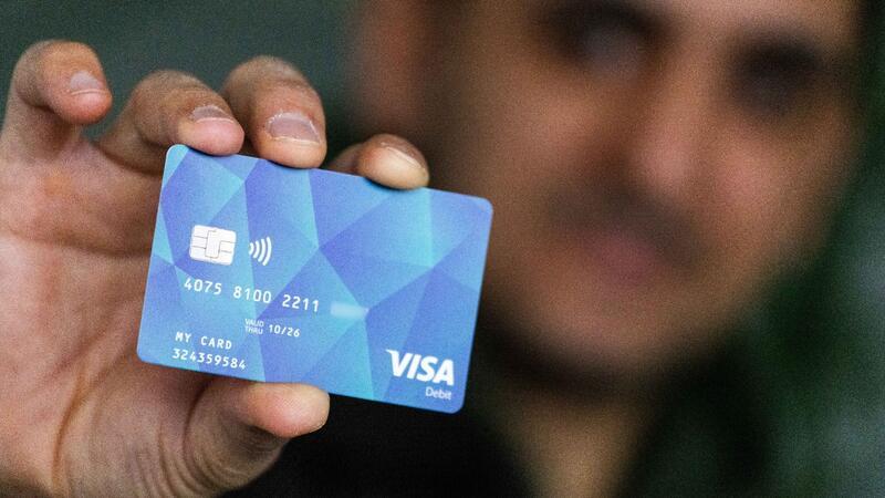 Ein Geflüchteter hält eine Debitcard in der Hand.