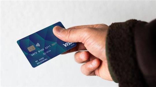 Ein Geflüchteter hält eine Debitkarte in der Hand.