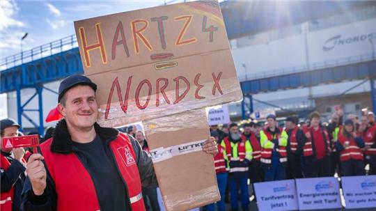 Ein Gewerkschaftsmitglied mit einem selbst gemalten Schild mit der Aufschrift „Hartz4 = Nordex“ beteiligt sich an dem kurzfristigen Warnstreik beim Windkraftanlagenherstellers Nordex.