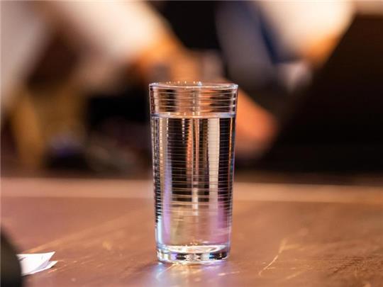 Ein Glas Wasser steht auf einem Tisch in der zum Gerichtssaal umfunktionierten Ritterakademie. Foto: Philipp Schulze/dpa