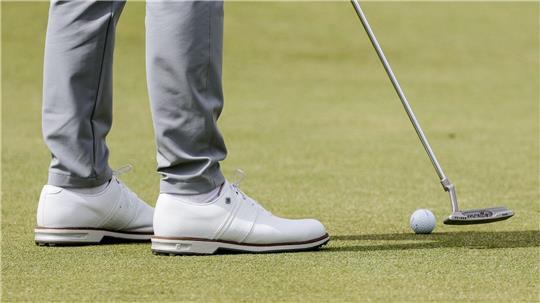 Ein Golfspieler puttet den Ball auf dem Grün.