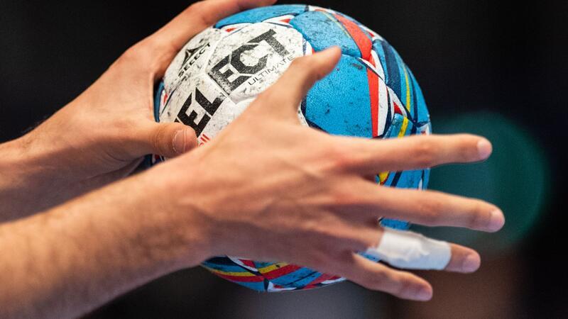 Ein Handballer hält den Spielball in den Händen.