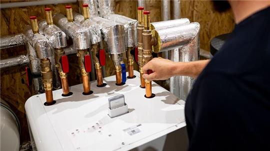 Ein Handwerker arbeitet an einer Wärmepumpe. Bei den Geräten ist die Nachfrage eingebrochen.