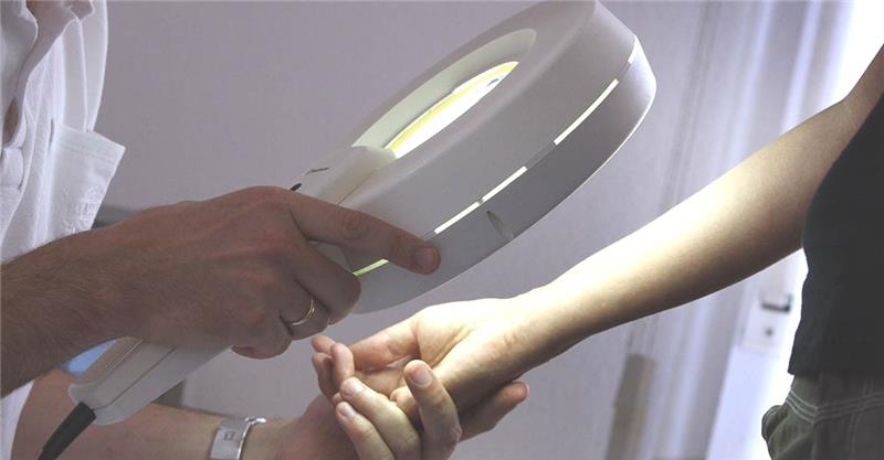 Hautkrebs-Erkrankungen haben sich verdoppelt Ein Hautarzt untersucht in seiner Praxis mit einem Vergrößerungsglas die Haut einer Patientin bei einer Hautkrebs-Früherkennung. Foto: picture alliance/dpa