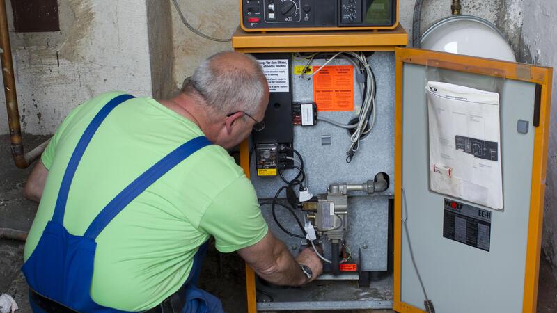 Ein Heizungsmonteur kontrolliert eine ältere Heizungsanlage.