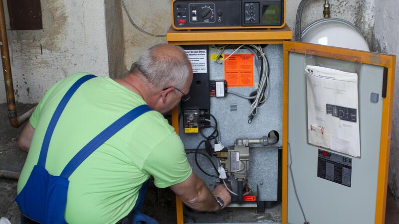Ein Heizungsmonteur kontrolliert eine ältere Heizungsanlage.