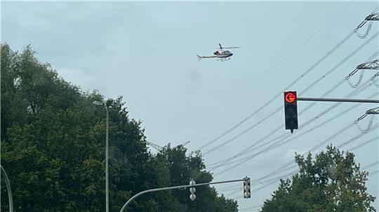 Ein Helikopter schwebt nahe der Stromleitung an der L111 Kreuzung Buxtehuder Straße/Altländer Straße.