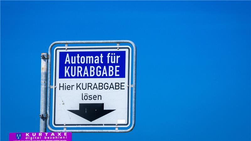 Ein Hinweisschild hängt über dem Zahlautomaten für die Entrichtung der Kurabgabe.