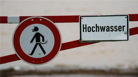 Ein Hochwasser-Schild steht an einem überfluteten Feld.