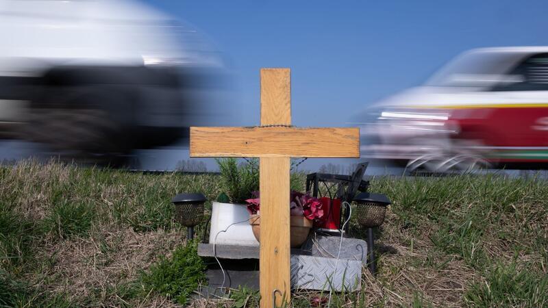 Ein Holzkreuz erinnert an einer Straße an das Opfer eines Verkehrsunfalls.