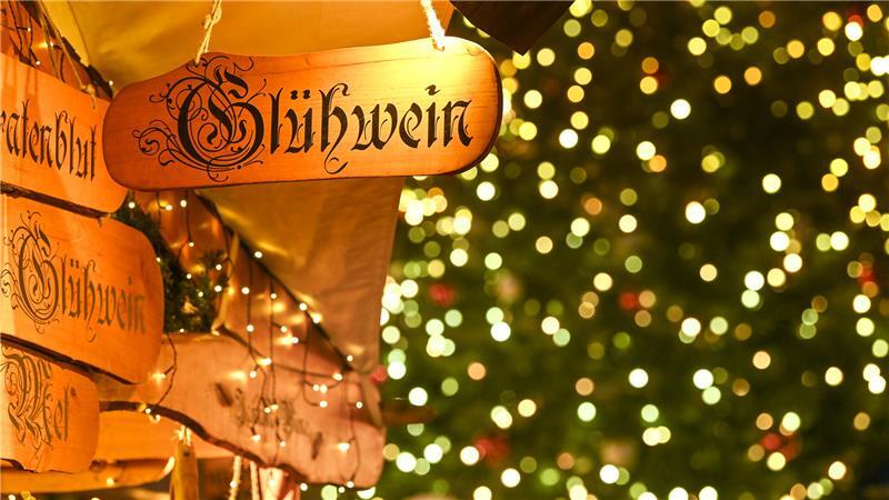 Ein Holzschild mit der Aufschrift „Glühwein“ hängt auf dem Halleschen Wintermarkt „Winterzauber“ an einem Marktstand.