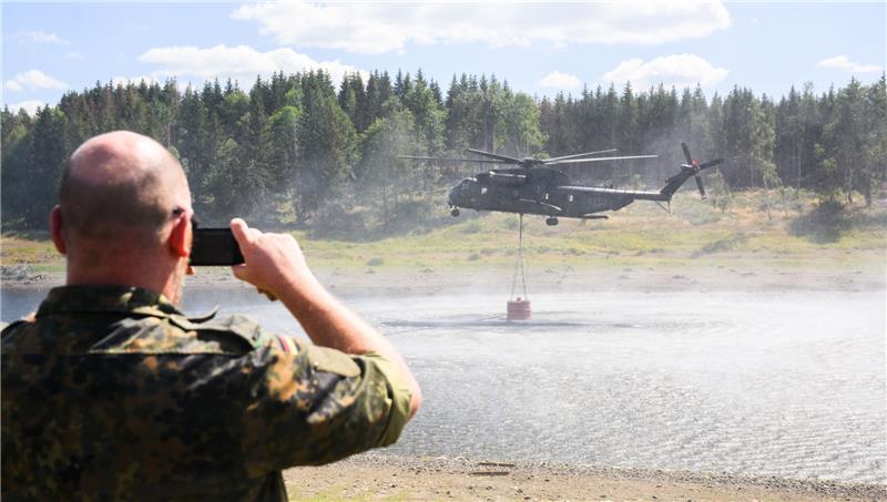 90 Feuerwehrleute kämpfen weiter gegen Waldbrand in Schierke Ein Hubschrauber CH-53 der Bundeswehr entnimmt Wasser aus der Mandelholztalsperre zur Bekämpfung eines Waldbrandes bei Schierke. Foto: Julian Stratenschulte/DPA