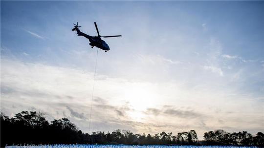 Ein Hubschrauber vom Typ Super Puma der Bundespolizei ist am Barneführer Holz im Einsatz, um einen Deich mit großen Sandsäcken zu sichern.