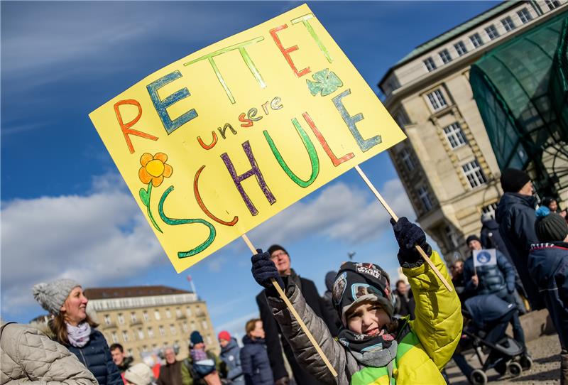 Ein Junge hält bei einer Demonstration auf dem Rathausmarkt für den Erhalt von 21 katholischen Schulen ein Plakat mit der Aufschrift "Rettet unsere Schule" in die Höhe. Foto Axel Heimken/dpa