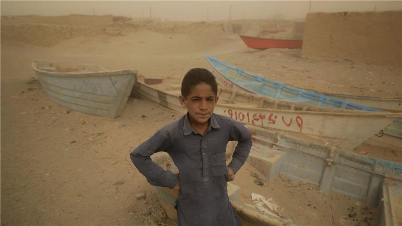 Ein Junge im Iran steht vor alten Booten, wo einst ein See war.