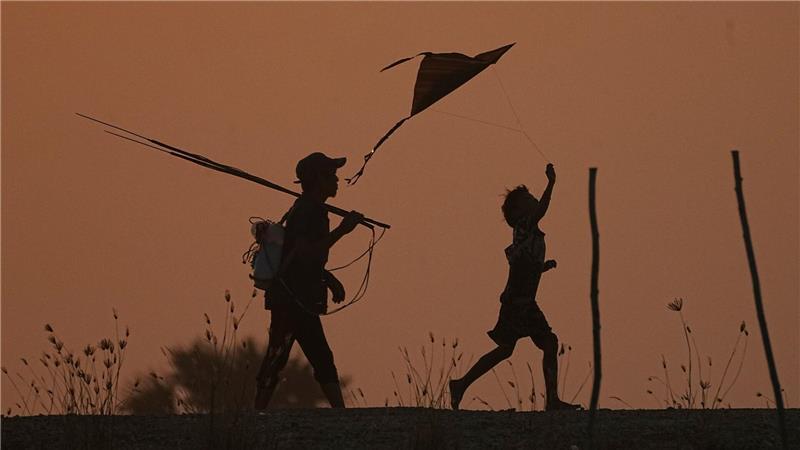 Ein Junge (r) lässt einen Drachen steigen, während er mit seinem Vater nach dem Fischen am Stadtrand von Phnom Penh nach Hause geht.