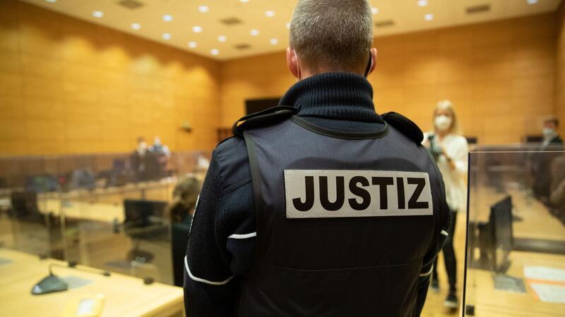 Genitalien der Ehefrau verstümmelt: Prozess gegen Frauenarzt Ein Justizbeamter steht in einem Gerichtssaal.