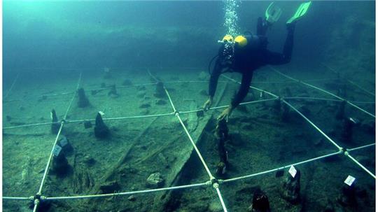 Ein Kanu wird Boden des Braccianosees ausgegraben. Die abgenutzten Überreste der mehr als 7000 Jahre alten Kanus lassen erahnen, wie ausgeprägt das Wissen über die Seefahrt bereits in der Jungsteinzeit war.