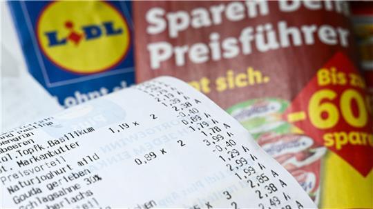 Ein Kassenzettel liegt auf Werbeprospekten mit Angeboten des Discounters Lidl.