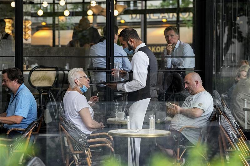 Ein Kellner bedient die Gäste im Außenbereich eines Restaurants. Foto: Michel Euler/AP/dpa