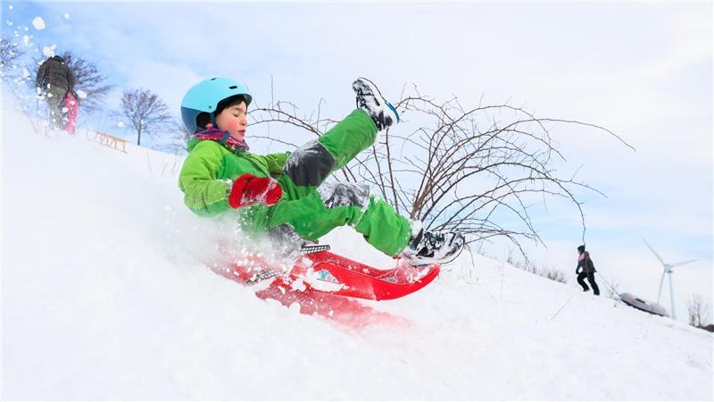 Ein Kind fährt mit seinem Schlitten am Kronsberg.