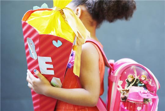 Ein Kind kommt mit Schultüte zur Einschulung. Foto: Oliver Berg/dpa